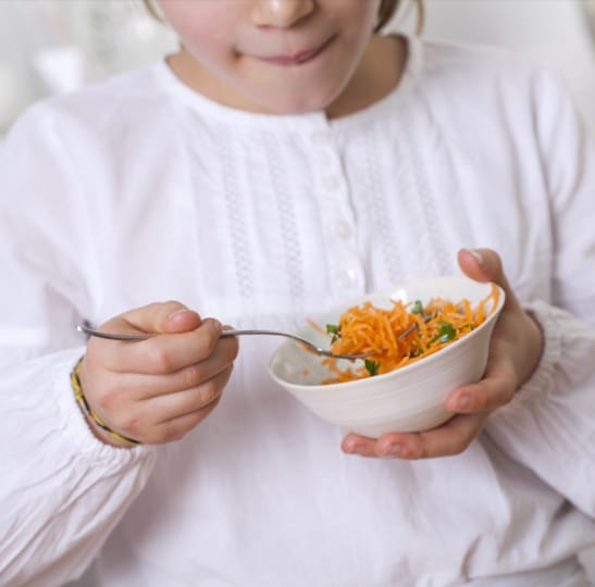 Un enfant en train de manger des carottes